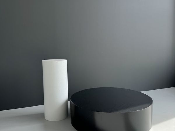 Baltas statinys ir juodas podiumas ant ratukų